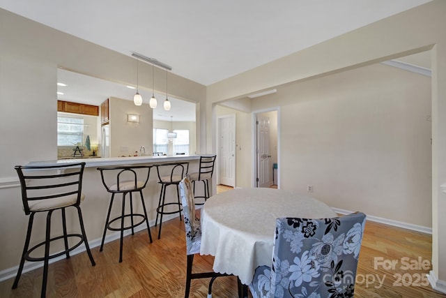 dining space featuring light wood-style flooring and baseboards