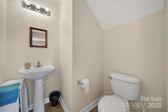 bathroom featuring toilet, baseboards, a sink, and lofted ceiling