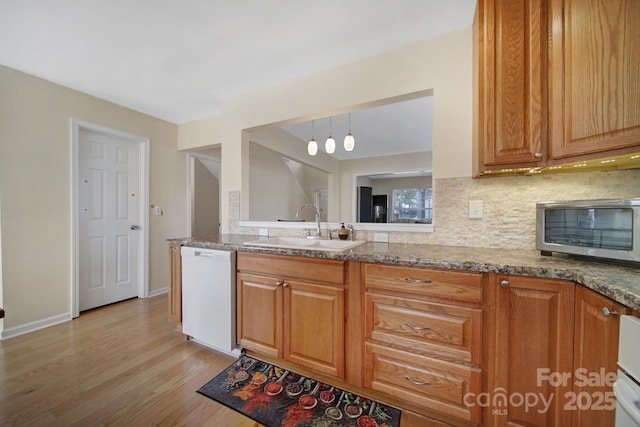 kitchen with light stone counters, decorative light fixtures, tasteful backsplash, a sink, and dishwasher