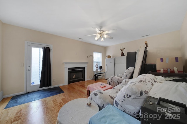 living room with a fireplace, plenty of natural light, wood finished floors, and visible vents