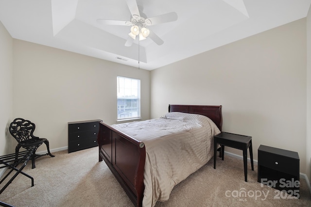 bedroom with light carpet, a ceiling fan, visible vents, baseboards, and a raised ceiling