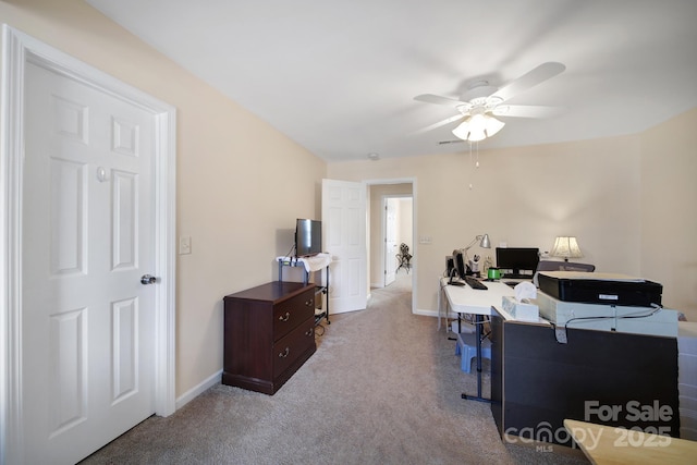 office area featuring light carpet, a ceiling fan, and baseboards