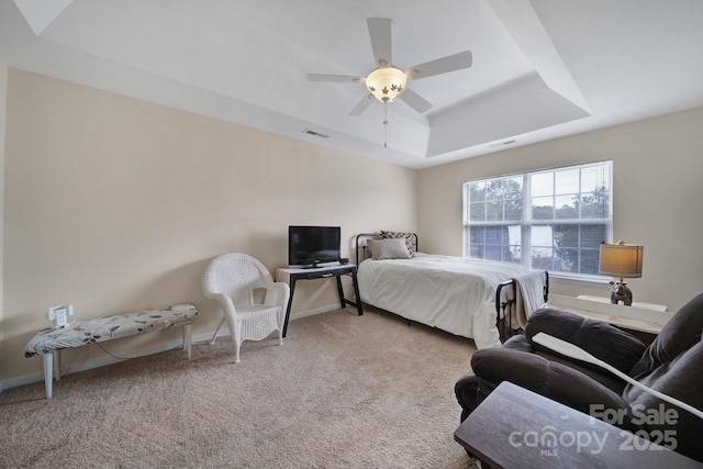 bedroom with light carpet, ceiling fan, a tray ceiling, and visible vents