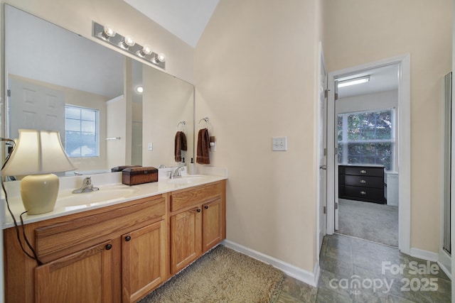 full bath featuring double vanity, plenty of natural light, baseboards, and a sink