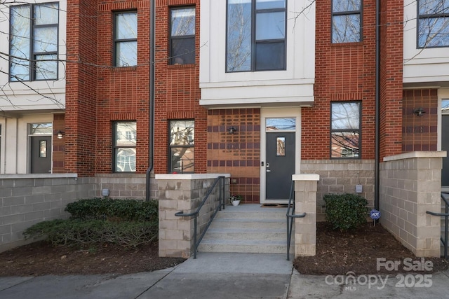 view of exterior entry featuring stone siding and brick siding