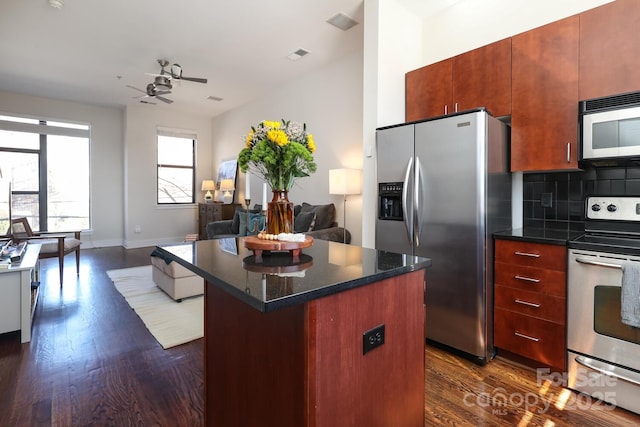 kitchen featuring decorative backsplash, appliances with stainless steel finishes, dark wood-type flooring, open floor plan, and a kitchen island