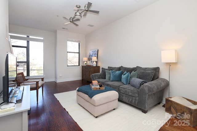 living area with a ceiling fan, wood finished floors, visible vents, and baseboards