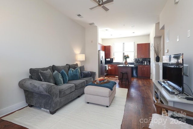 living room with a ceiling fan, light wood-type flooring, visible vents, and baseboards