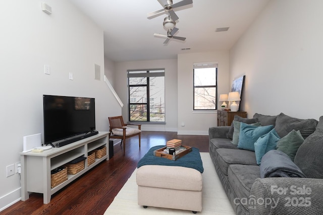 living area with dark wood-style floors, visible vents, baseboards, and a ceiling fan