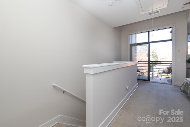 hallway with attic access, visible vents, baseboards, carpet, and an upstairs landing