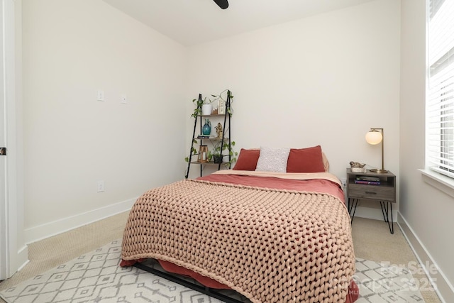 bedroom featuring a ceiling fan, light carpet, and baseboards