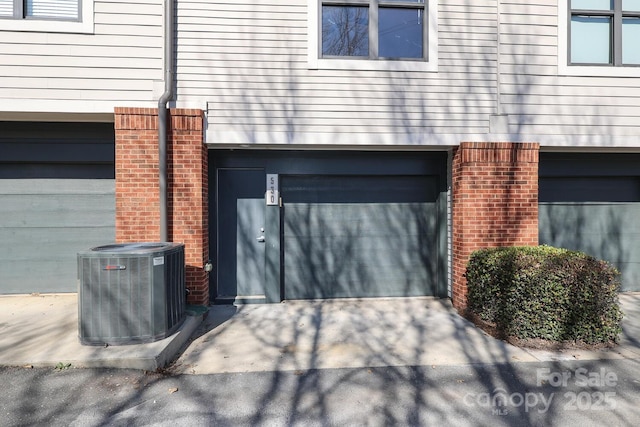 garage with concrete driveway and central AC