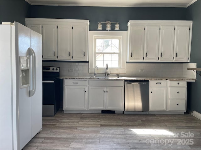 kitchen featuring light stone counters, light wood-style flooring, stainless steel appliances, white cabinets, and tasteful backsplash