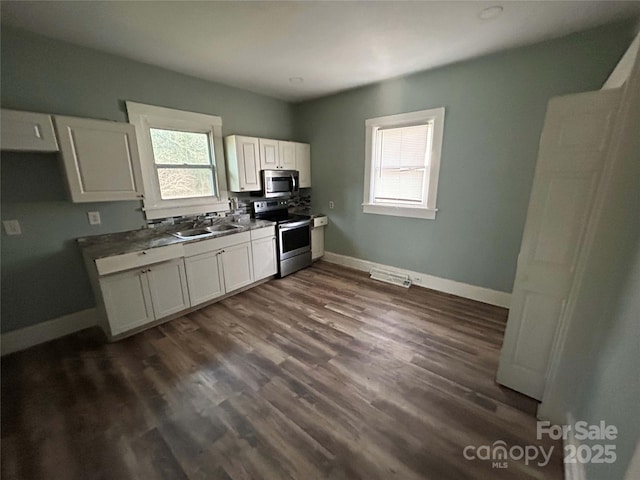 kitchen featuring baseboards, appliances with stainless steel finishes, plenty of natural light, and white cabinets