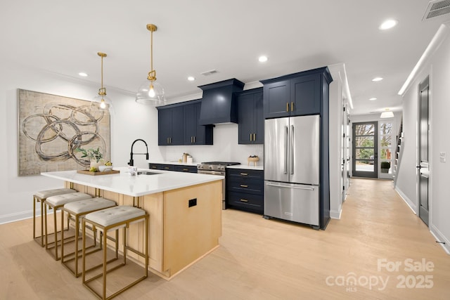 kitchen featuring a breakfast bar area, visible vents, a sink, custom range hood, and appliances with stainless steel finishes