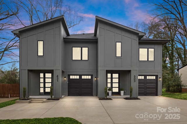 modern home with board and batten siding, driveway, and fence