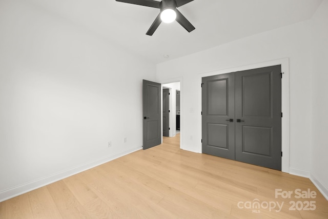 unfurnished bedroom with light wood-type flooring, baseboards, a closet, and a ceiling fan