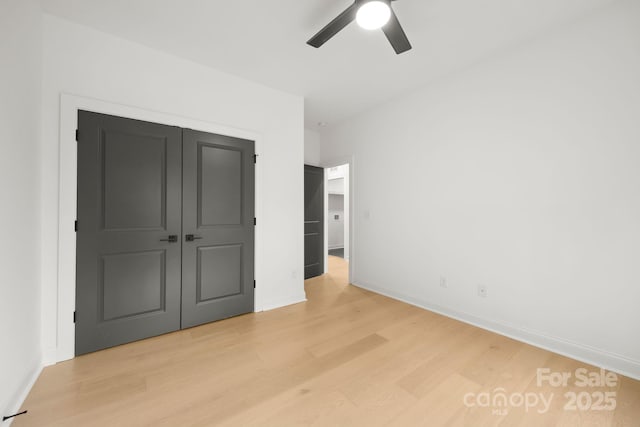 unfurnished bedroom featuring a closet, baseboards, light wood finished floors, and ceiling fan