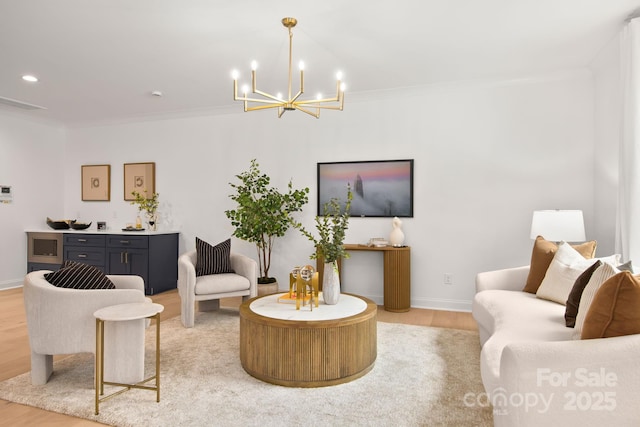 living room featuring light wood-style flooring, ornamental molding, recessed lighting, baseboards, and a chandelier