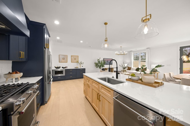 kitchen featuring light brown cabinets, wall chimney range hood, light countertops, stainless steel appliances, and a sink