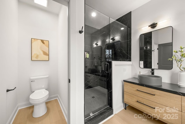 full bath featuring toilet, wood finished floors, a shower stall, baseboards, and vanity