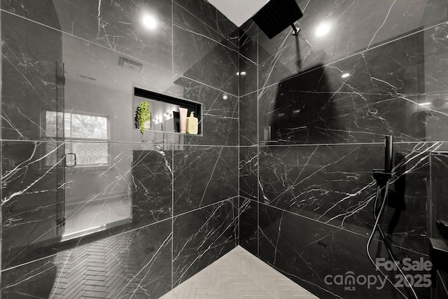 bathroom with visible vents and a marble finish shower