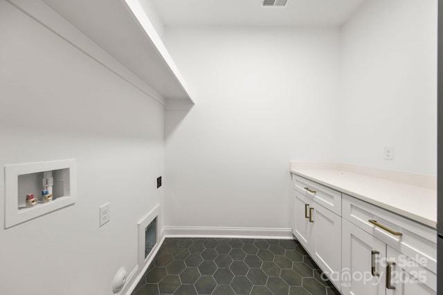 clothes washing area with visible vents, dark tile patterned flooring, cabinet space, baseboards, and hookup for a washing machine