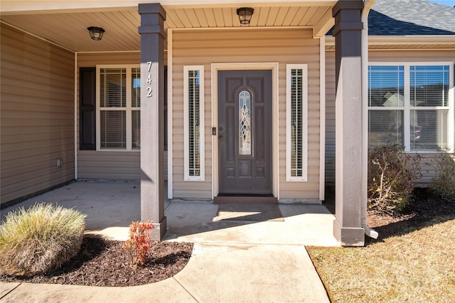 doorway to property featuring a shingled roof and a porch