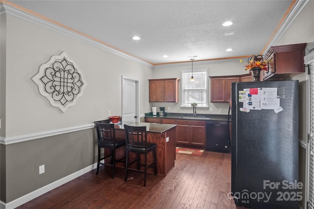 kitchen with a peninsula, a sink, a kitchen breakfast bar, black appliances, and dark countertops