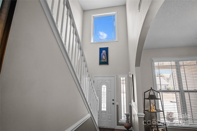 entryway with arched walkways, stairway, and a towering ceiling