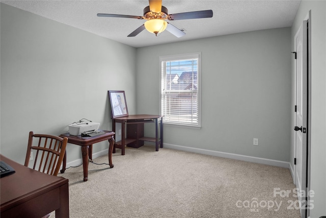 home office with a textured ceiling, baseboards, a ceiling fan, and light colored carpet