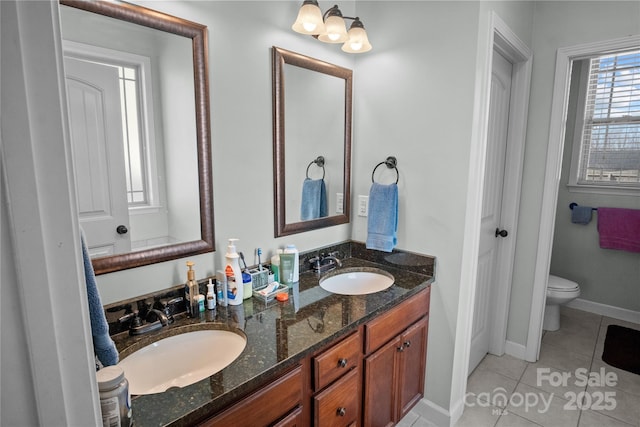 bathroom with baseboards, double vanity, a sink, and tile patterned floors