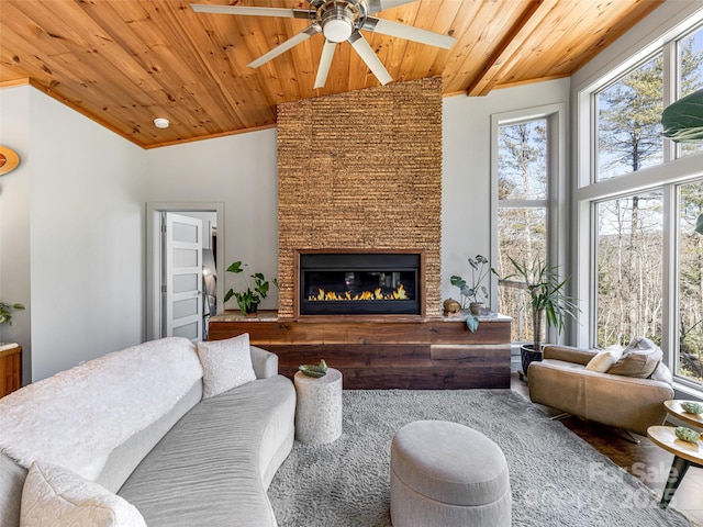 living area with high vaulted ceiling, wood ceiling, a fireplace, and ceiling fan