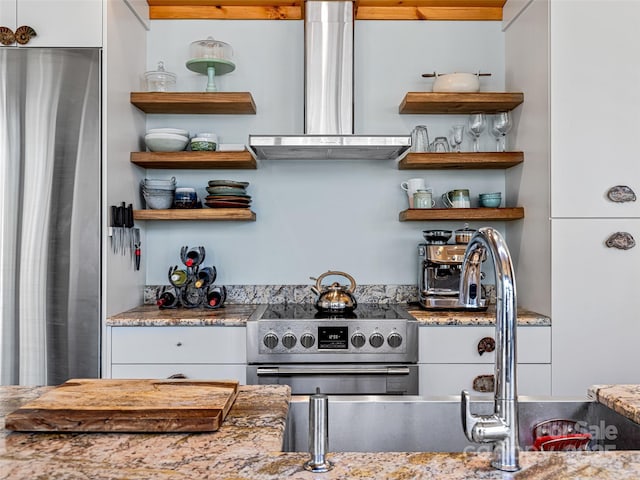 kitchen with appliances with stainless steel finishes, exhaust hood, white cabinets, and open shelves