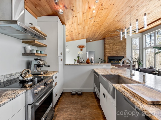 kitchen with a stone fireplace, wooden ceiling, a sink, wall chimney range hood, and stainless steel electric range