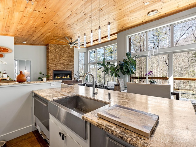 kitchen with light stone counters, dark wood-type flooring, a fireplace, a sink, and wood ceiling