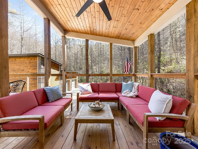 sunroom / solarium with ceiling fan, wooden ceiling, and a view of trees