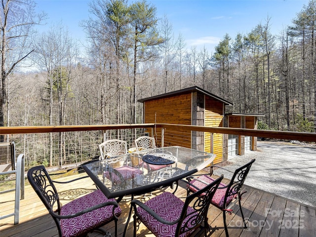 deck with outdoor dining area and a view of trees