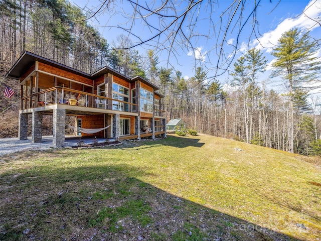 exterior space with a yard, a deck, and a wooded view