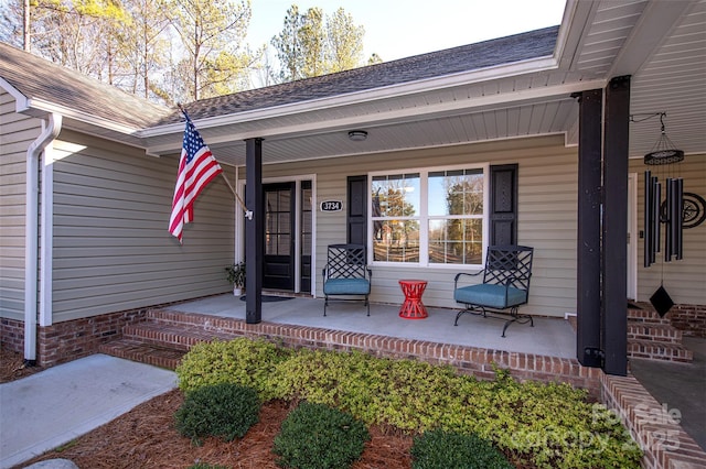 view of exterior entry with a porch and a shingled roof