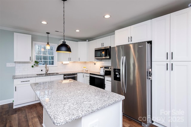 kitchen with stainless steel appliances, white cabinets, a sink, and a kitchen island