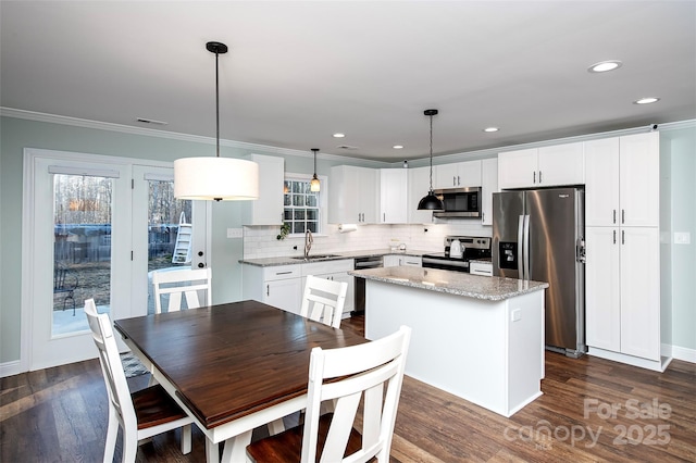 kitchen with a center island, pendant lighting, appliances with stainless steel finishes, white cabinets, and a sink