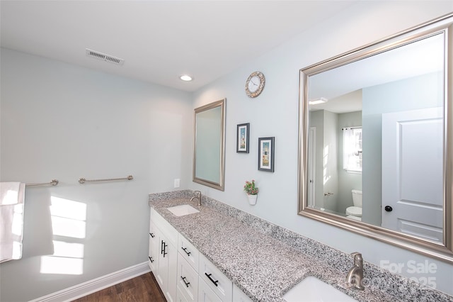 bathroom with visible vents, a sink, toilet, and double vanity