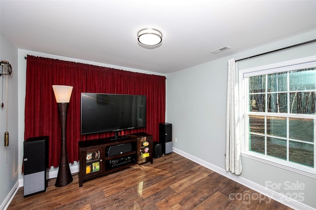 living room with dark wood finished floors, visible vents, and baseboards