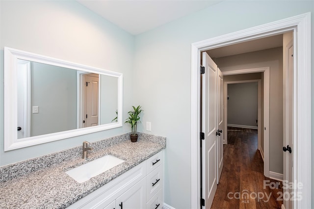 bathroom with baseboards, wood finished floors, and vanity