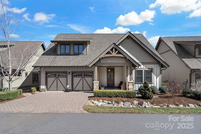 view of front of house with roof with shingles, decorative driveway, and board and batten siding