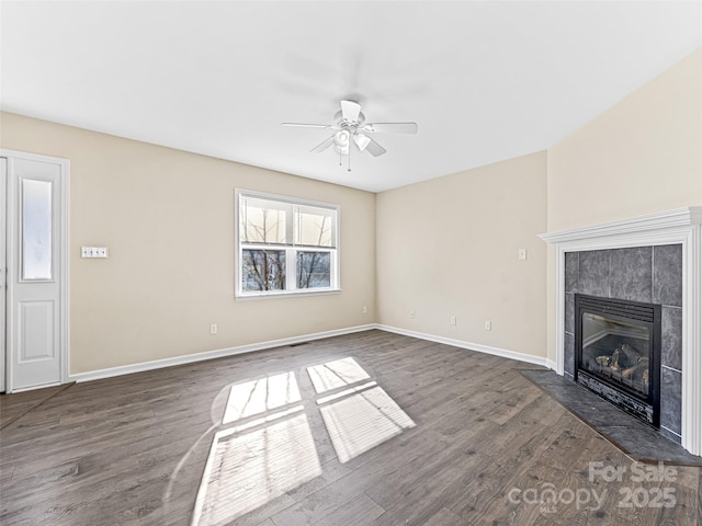 unfurnished living room with a ceiling fan, dark wood-style flooring, a fireplace, and baseboards