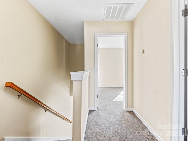 corridor with visible vents, light carpet, an upstairs landing, and baseboards