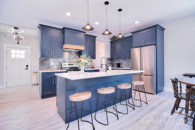 kitchen featuring an island with sink, stainless steel appliances, light countertops, and a kitchen breakfast bar