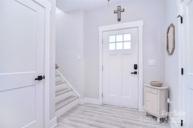 foyer with light wood-style flooring, stairway, and baseboards